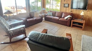 Una sala de estar acogedora con un sofá modular, un sillón mecedor y un televisor instalado en la pared.