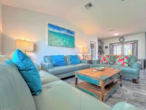 A living room with a sofa, a coffee table, and a painting of a beach scene.