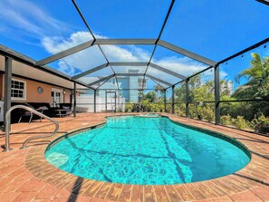Une piscine avec un bassin aux eaux d’un bleu limpide, entourée d’une terrasse couverte d’où l’on peut admirer un immeuble d’habitation en arrière-plan.