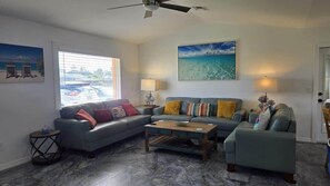 A living room with a gray sofa, a wooden coffee table, and a ceiling fan.