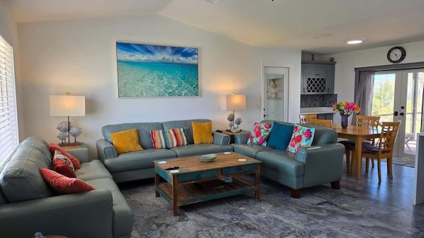 A living room with a sofa, coffee table, and a painting of a beach scene.