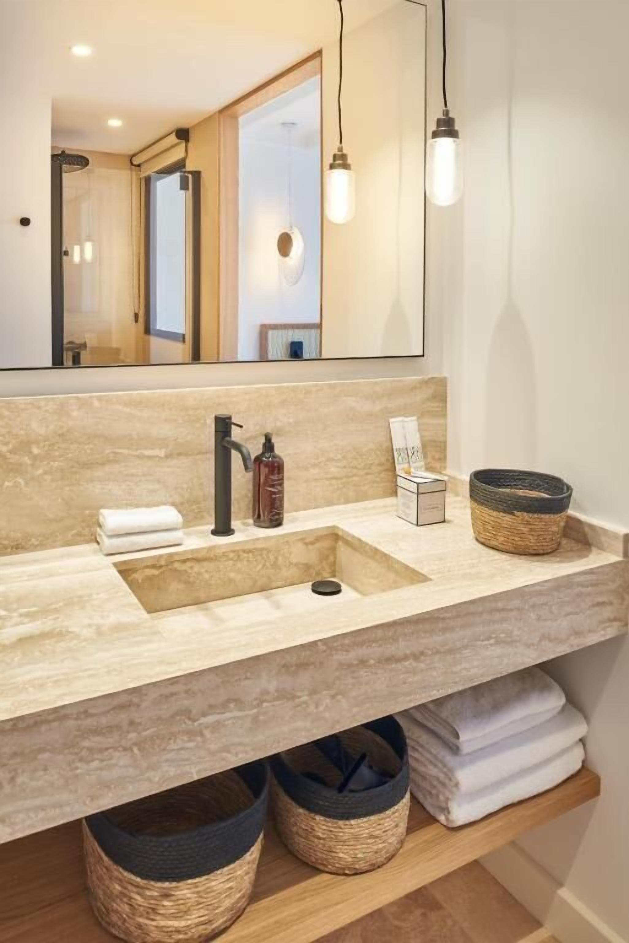 A bathroom with a large mirror, two pendant lights, a sink with a faucet, and a towel rack.