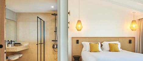 A modern hotel room with a large bed, two bedside lamps, a wooden headboard, and a small bedside table.