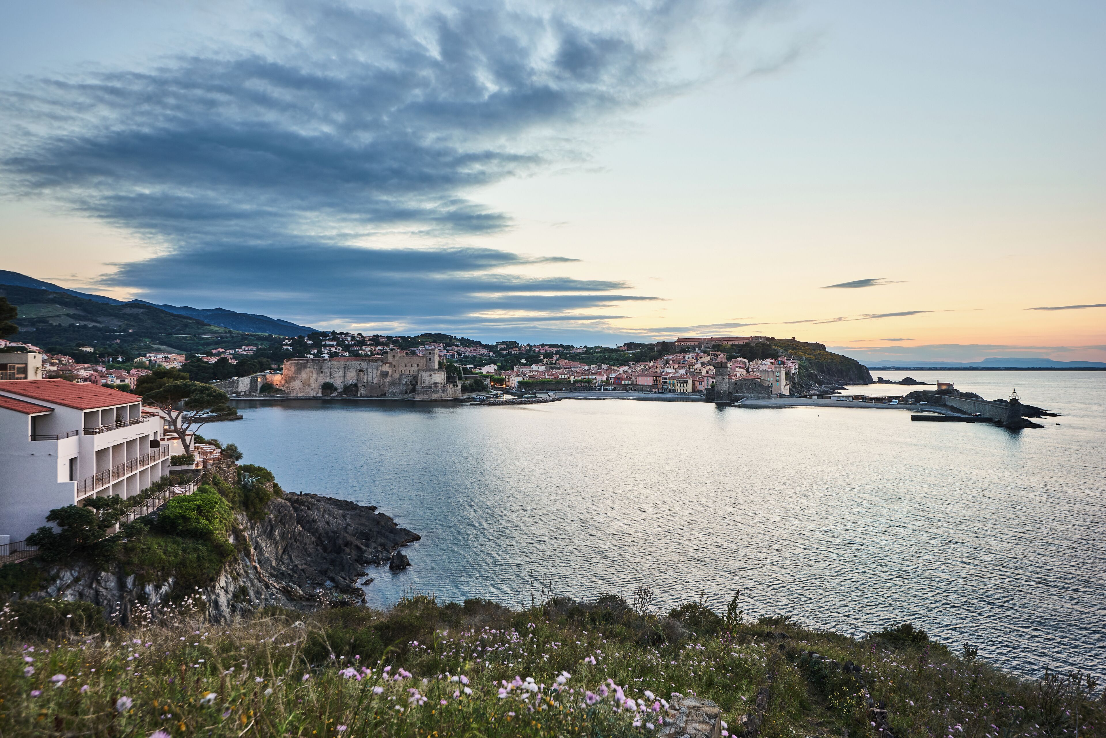 A coastal town with a historic fortification, a marina, and residential buildings along the waterfront.