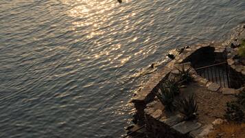 A stone pathway leading to a body of water with reflections of the sun.
