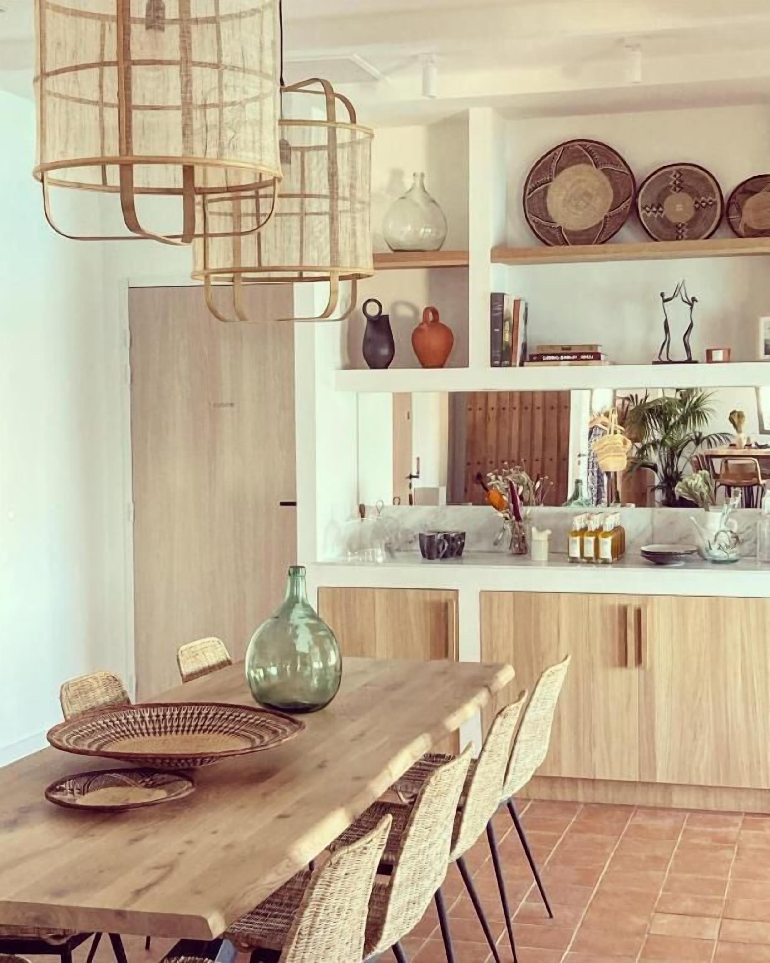 Une cuisine moderne avec un îlot central en bois, des chaises en osier et un luminaire suspendu.