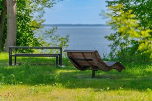 A park bench and a unique wooden sculpture in a grassy area with a lake view.