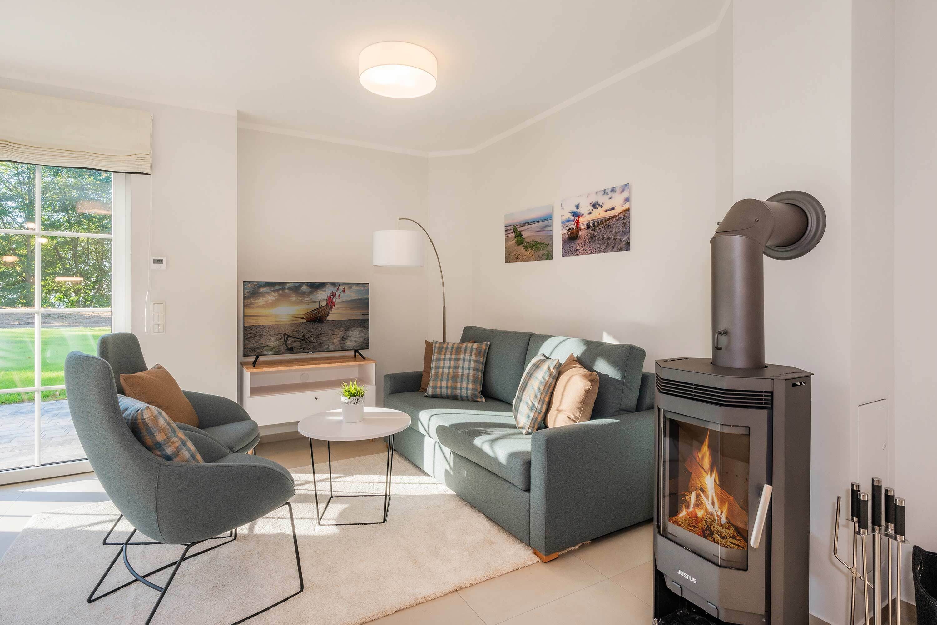 A modern living room with a grey sofa, a small coffee table, a TV, and a wood-burning stove.