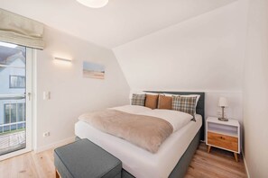 A bedroom with a bed, bedside table, and a view of the outside.