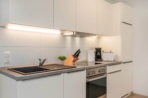 A modern kitchen with a built-in oven, a sink, and a coffee maker. - Stylish vacation home in a fishing village with garden, 3 floors & infrared cabin on the ground floor (Zirchow)