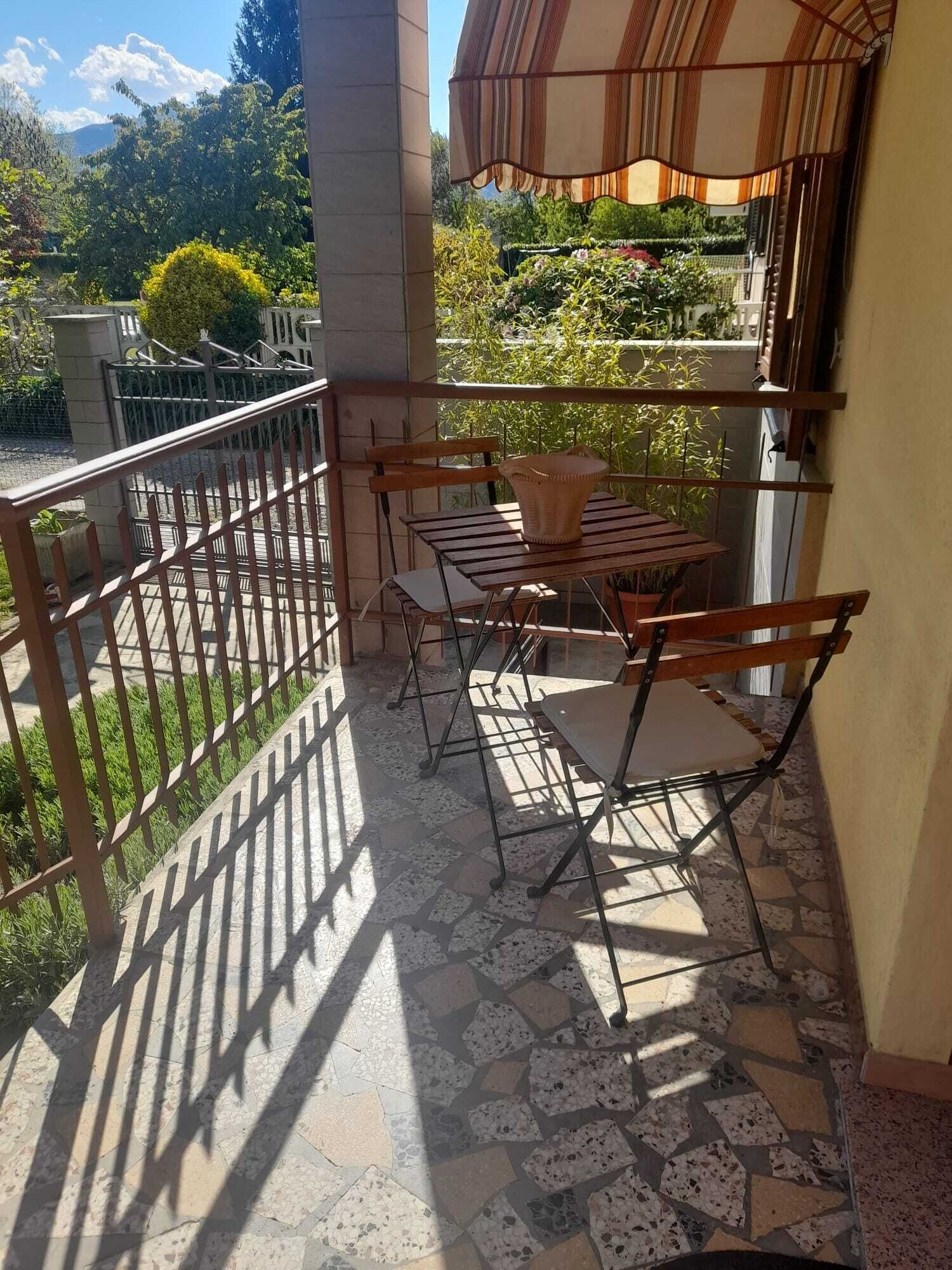 Ein Balkon mit Fliesenboden, Metallgeländer und einem Tisch mit Stühlen.