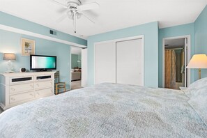 A bedroom with a bed, a television, a dresser, and a closet.