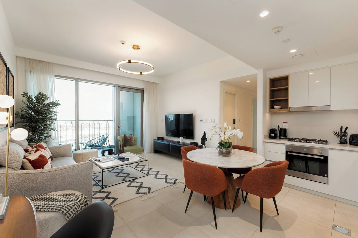 A modern apartment with a dining area, kitchen, living room, and a balcony with a view.
