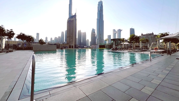 A swimming pool with a city skyline in the background, including tall buildings.