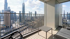 A balcony with a city view, a metal railing, a small table, and a sofa.