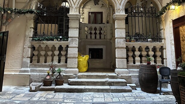 An arched entrance with a stone facade, a wooden door, and a small balcony with railings. - Dimora Riccardi San Nicola (Bari)