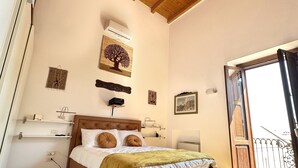 A bedroom with a wooden ceiling, a bed with a headboard, a window with a view, and a door leading to an outdoor balcony. - Dimora Riccardi San Nicola (Bari)
