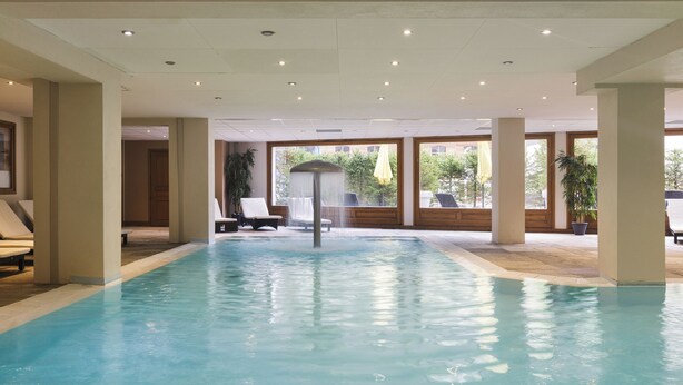 An indoor swimming pool with clear water, surrounded by lounge chairs and large windows offering views of the outdoors. - Vallorcine Loriaz 41 ski in / ski out (Vallorcine)