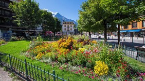 A hotel with a mountain view, a garden with colorful flowers, and a street with shops and pedestrians. - Vallorcine Loriaz 41 ski in / ski out (Vallorcine)