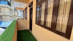 A corridor with artificial grass, wooden doors, and windows with curtains. - Arrived Inn (Gyalshing)
