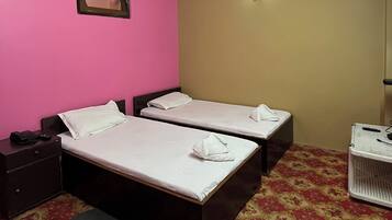 A hotel room with two beds, a nightstand, a lamp, and a patterned carpet.