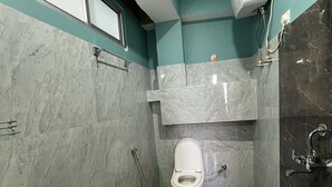 A bathroom with a bathtub, toilet, and shower. - Arrived Inn (Gyalshing)