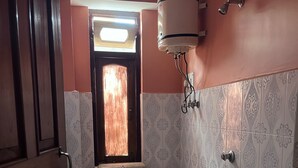 A compact bathroom with a toilet, sink, and a window. - Arrived Inn (Gyalshing)