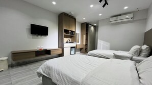 A modern hotel room with two beds, a TV, a minibar, and a built-in wardrobe.