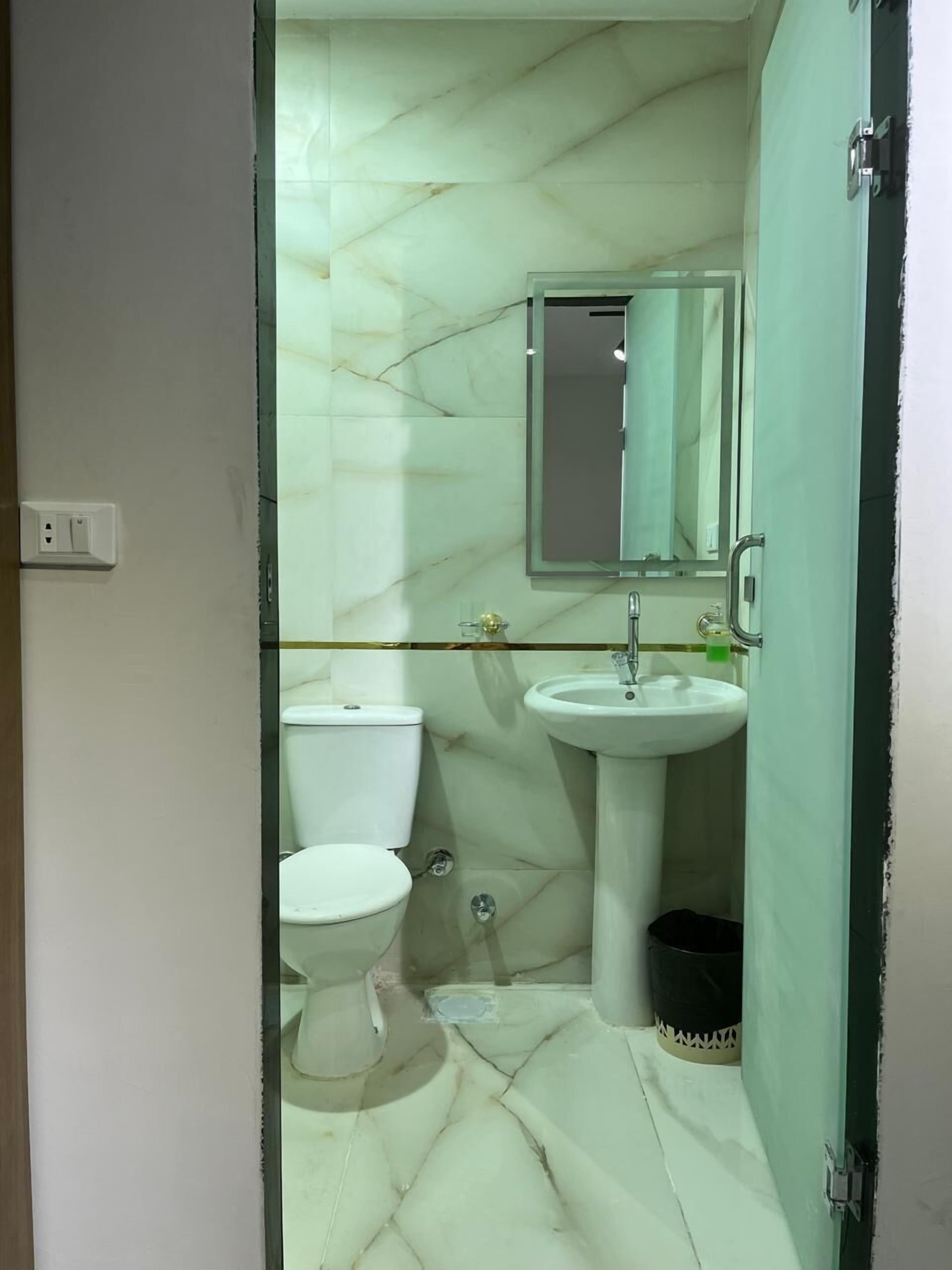 Een badkamer met toilet, wastafel en spiegel.
