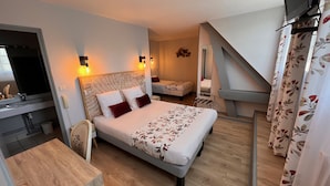 A compact hotel room with a bed, a small desk, a mirror, and a staircase. - Logis hôtel des voyageurs (Tarnac)