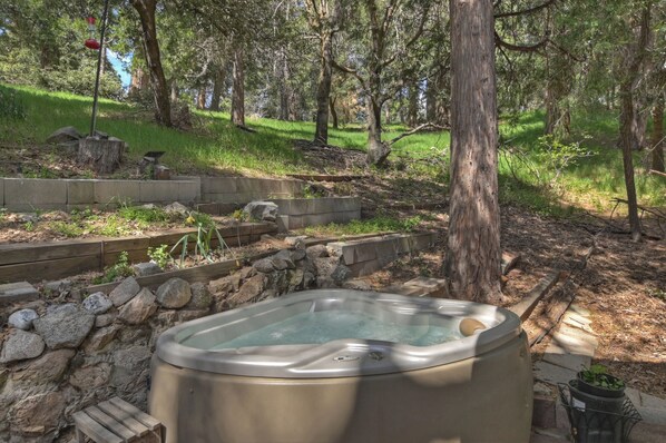 Relax in a serene hot tub surrounded by lush trees and a wooden deck.