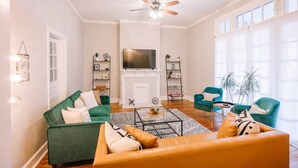 A living room with a fireplace, a television, and two green sofas.