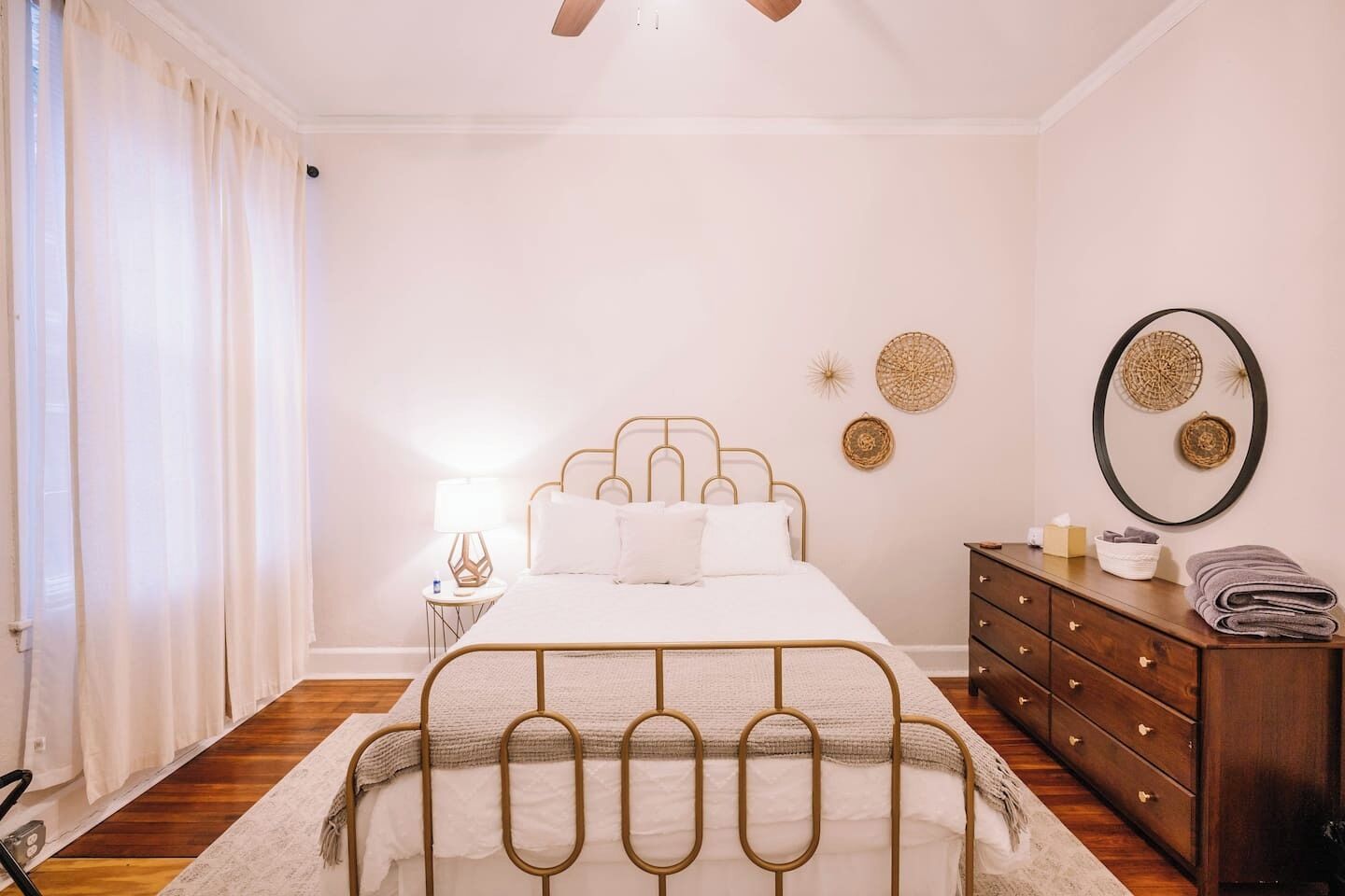 Un dormitorio con cama, cómoda, mesita de noche y espejo.