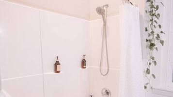 A modern bathroom with a bathtub, shower, and two hand soap dispensers.