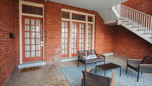 A covered patio with brick walls, a staircase, and outdoor seating.