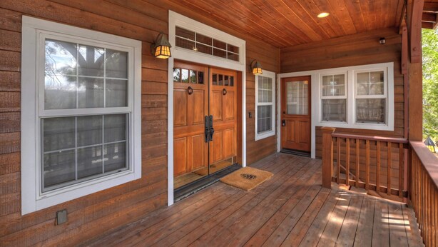 A wooden porch with a double door, a small window, and a wooden railing.