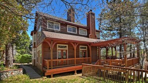 A two-story wooden house with a porch and a covered deck area.