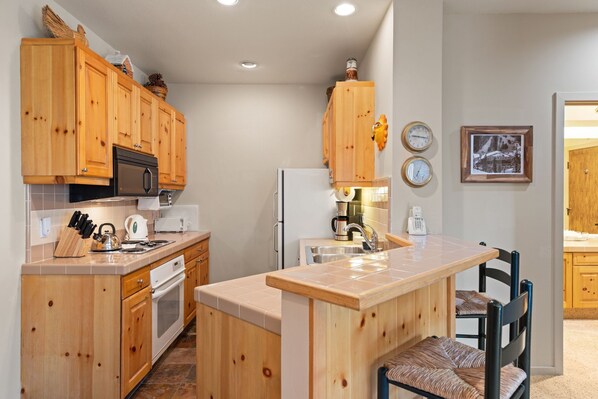 A kitchen with wooden cabinets, a central island, and a dining area with a chair.