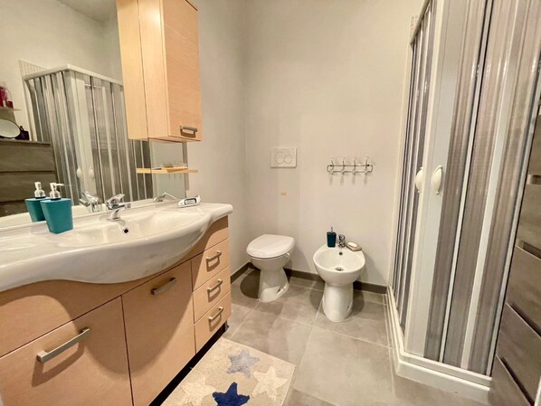 Un baño con lavamanos, inodoro, bidé y ducha.