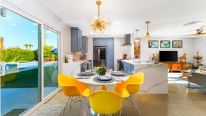 A modern kitchen with a central island, bright yellow chairs, and a large window overlooking a swimming pool. - 30% Off September Perfect 4 Families Pool, Jacuzzi (Palm Springs)