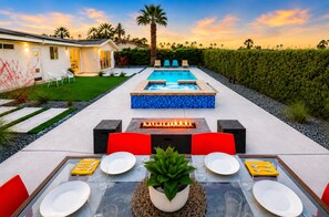 A pool area with a hot tub, outdoor seating, and a dining table set for two.