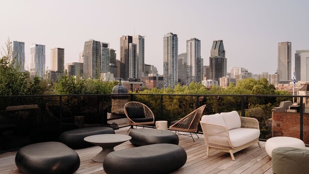 A rooftop terrace with modern seating, a city skyline view, and a wooden deck. - Maison Grinder (Montréal)