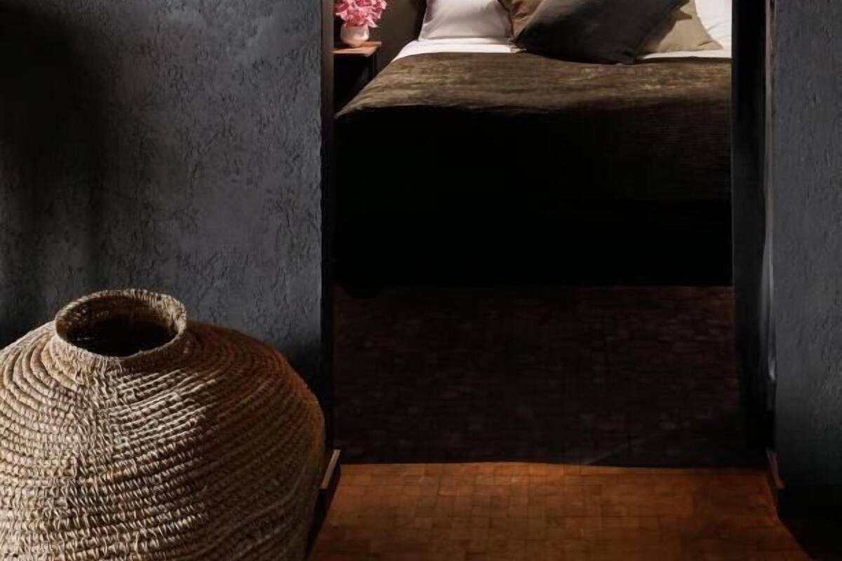 A cozy bedroom with a bed, bedside lamp, and a wall-mounted light fixture.