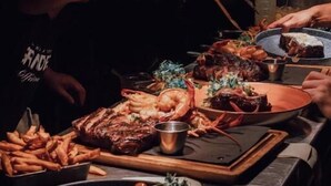 A dining table with various dishes, including seafood and steak, in a dimly lit setting. - Maison Grinder (Montréal)