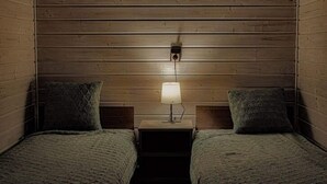 A small, cozy room with wooden walls and two beds. There is a nightstand with a lamp between the beds. - Holiday Home in Dziwnówek near Baltic Sea (Dziwnówek)