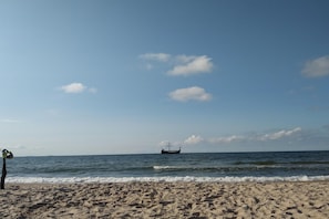 A beach with a boat in the distance and a clear sky.