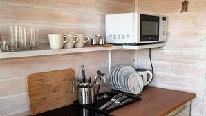 A compact kitchen with a microwave, a coffee maker, and a set of utensils on the counter. - Holiday Home Dziwnówek near Baltic Sea (Dziwnówek)