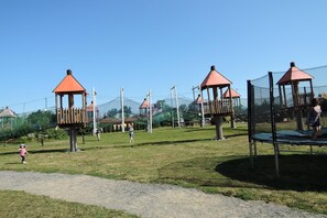 A playground with multiple play structures, including swings and climbing frames, surrounded by a safety net.