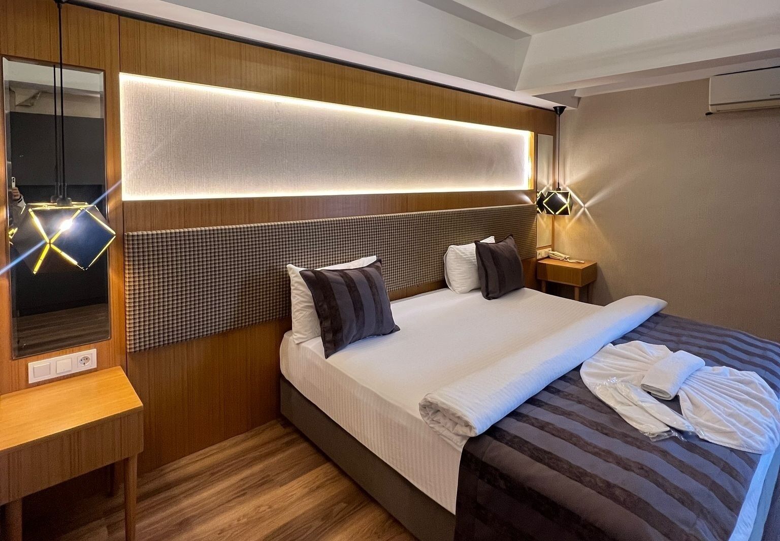 Ein Hotelzimmer mit einem Bett, Nachttischen, einem Spiegel und einer Wandleuchte.