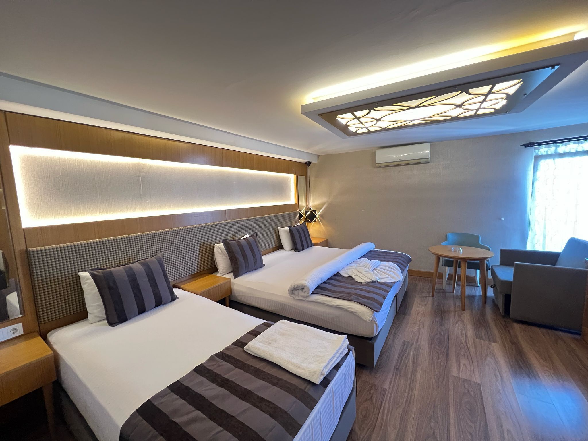 Una habitación de hotel con dos camas, una mesita y una silla.